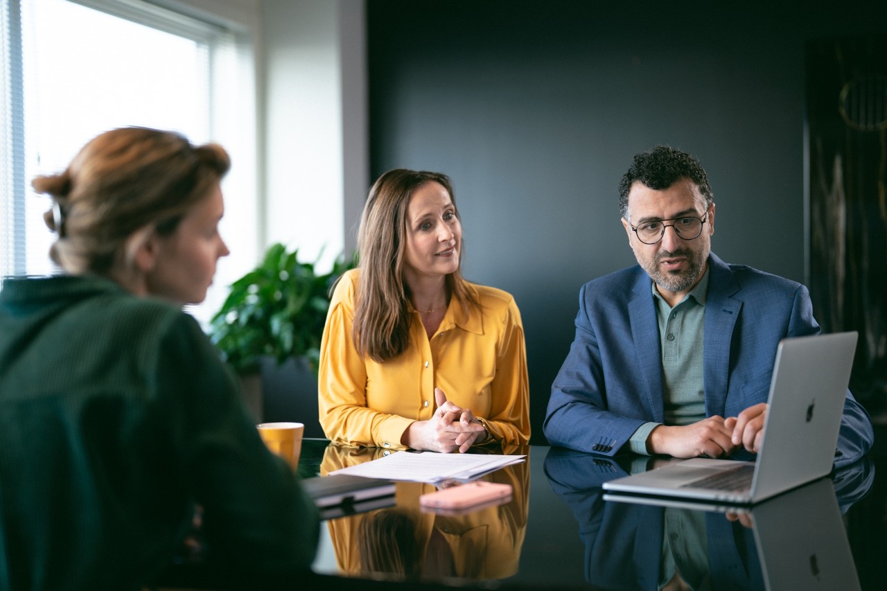 Stel heeft gesprek met consulent en kijken op laptop en naar papieren