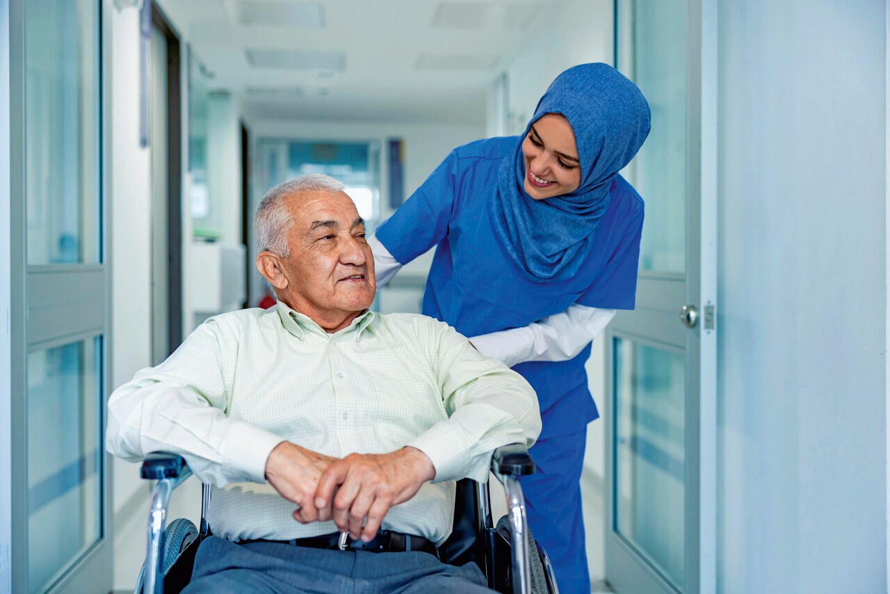 Thuiszorg verpleger houdt hand vast van iemand waarbij de bloeddruk wordt gemeten