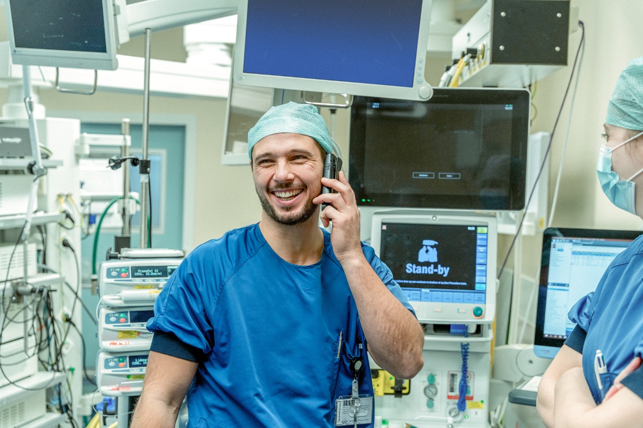 Lachende verpleger aan telefoon in behandelkamer