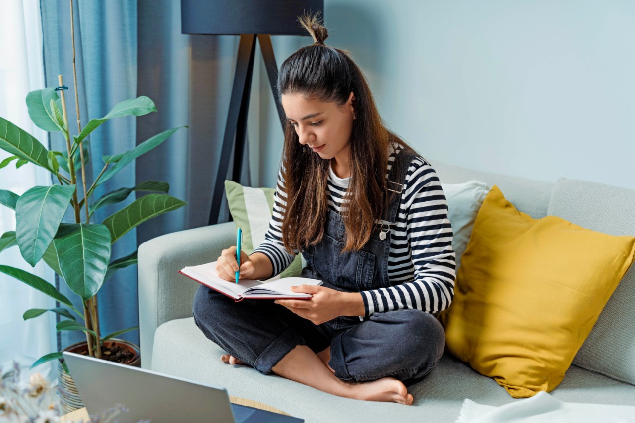 A young woman dives into her back-to-school routine, jotting down notes in her notebook, blending old-school charm with a modern study vibe.