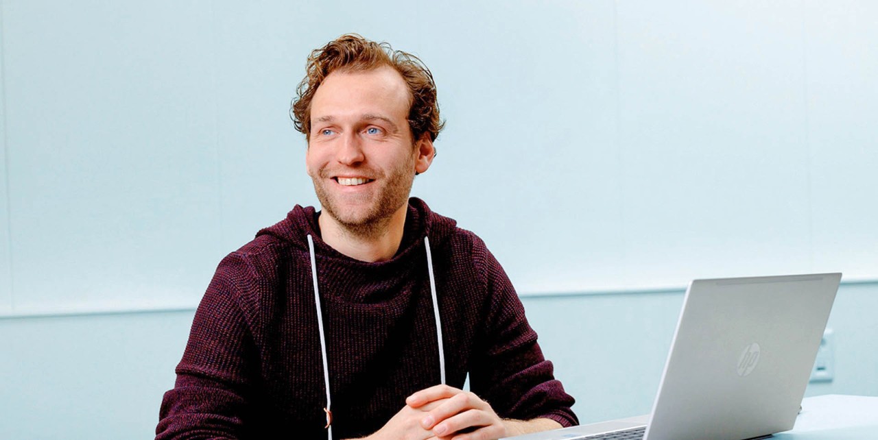 Portret Sjef glimlacht achter laptop