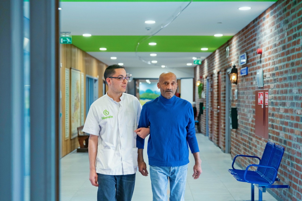 Verzorger loopt arm in arm met client