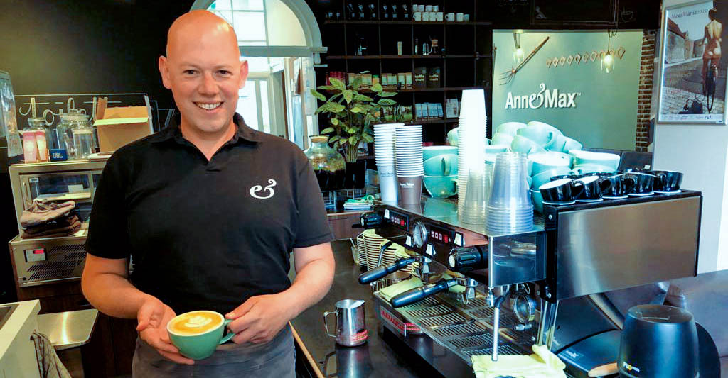 Paul glimlacht met cappuchino in zijn handen