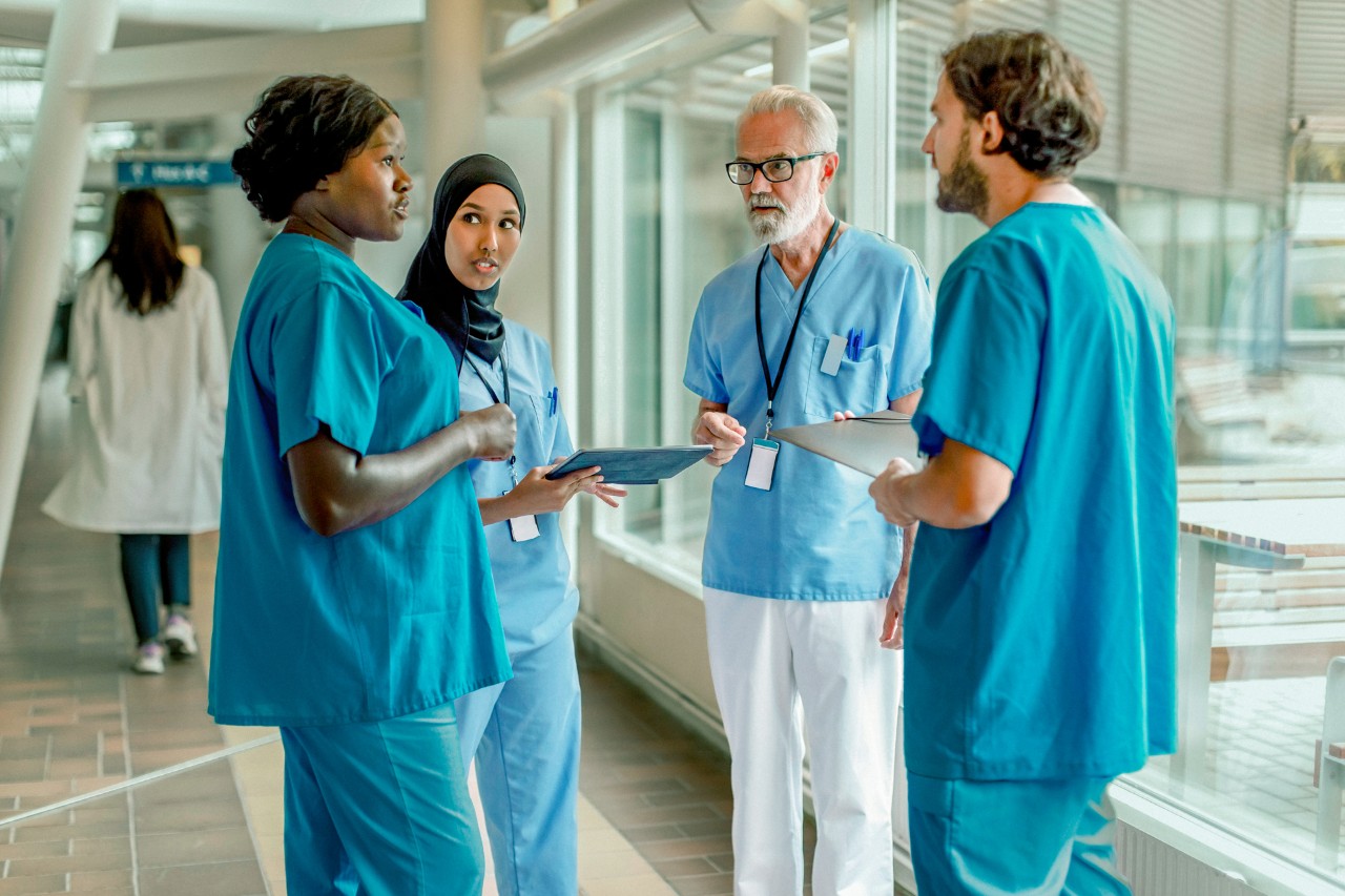ziekenhuispersoneel (4 personen) overleggen op gang ziekenhuis