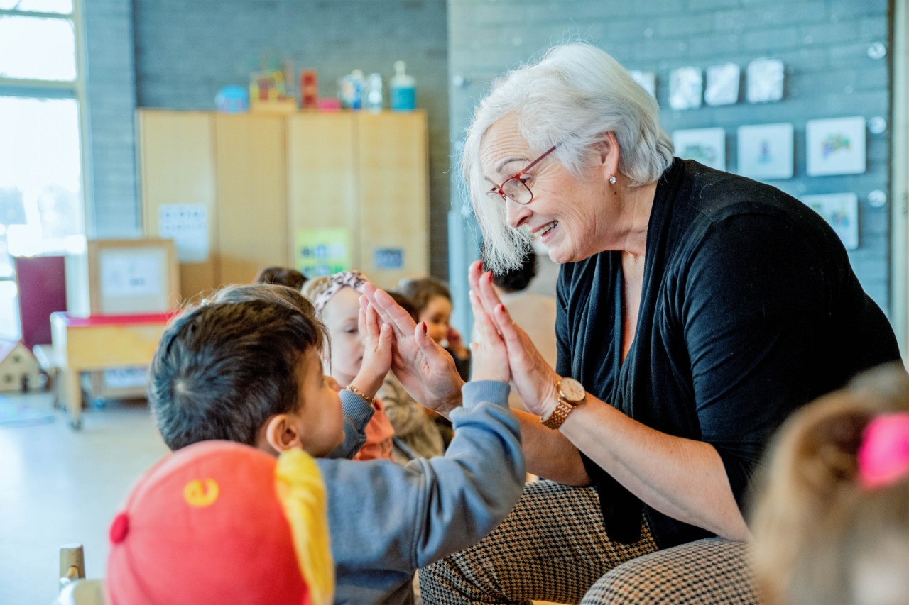 oudere juf high five aan kinderen