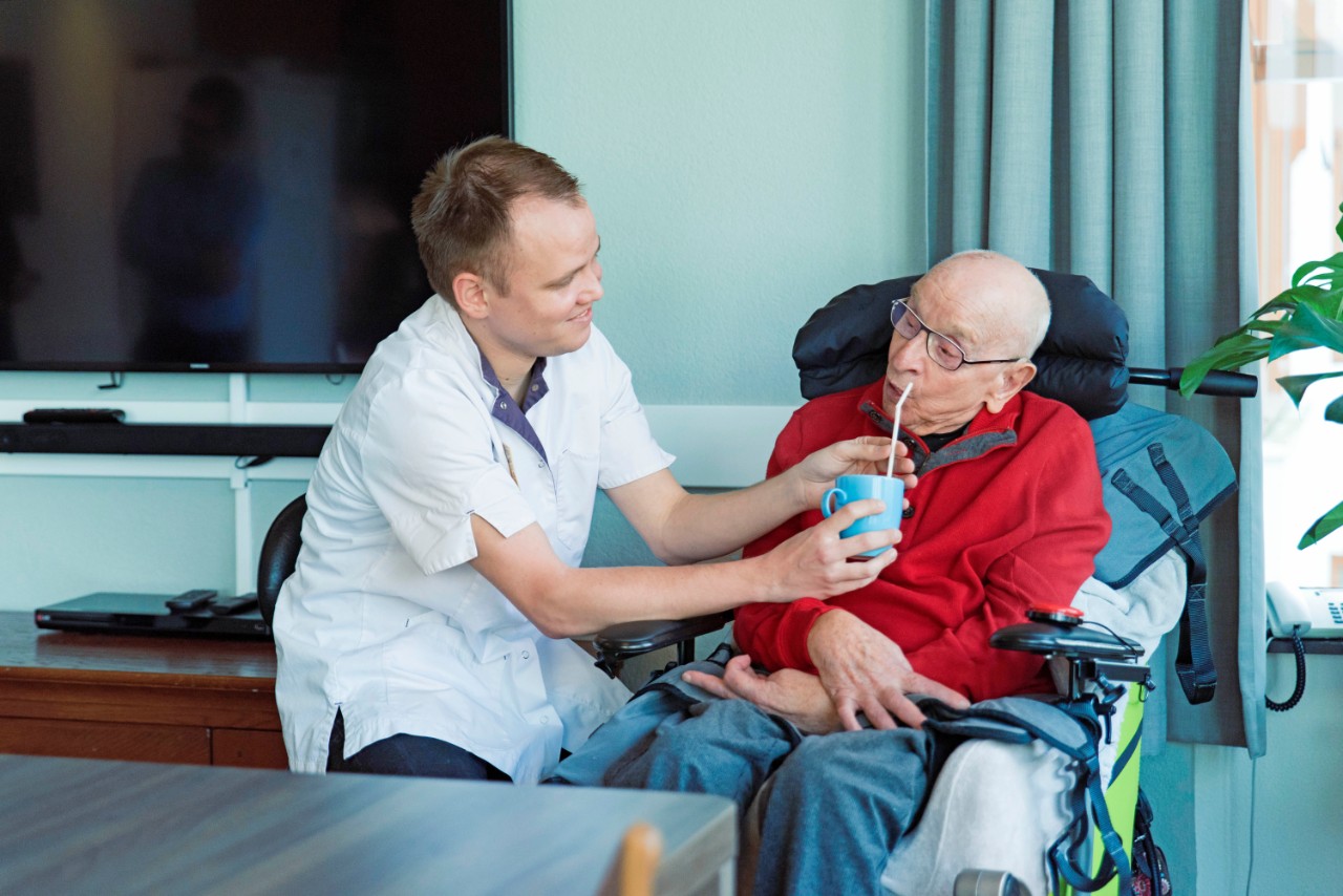 verpleegkundige geeft oude man drinken